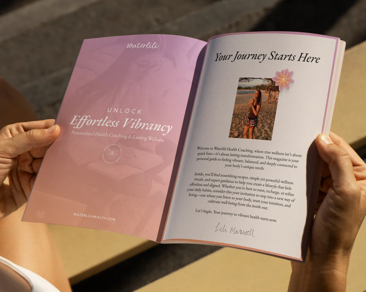 A person holds open a Waterlili Health Coaching magazine. The left page has a soft pink gradient background with the title “Unlock Effortless Vibrancy” and a tagline about personalized health coaching. The right page includes a welcome message titled “Your Journey Starts Here,” with a photo of Lili Maxwell on a beach and her signature at the bottom.